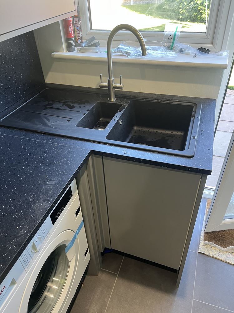 Black composite kitchen sink with a brushed swan-neck mixer tap
