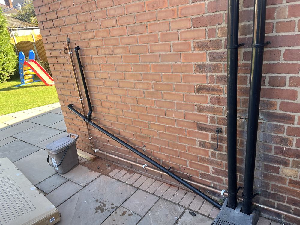 Neatly clipped external waste and copper supply pipework on a brick wall